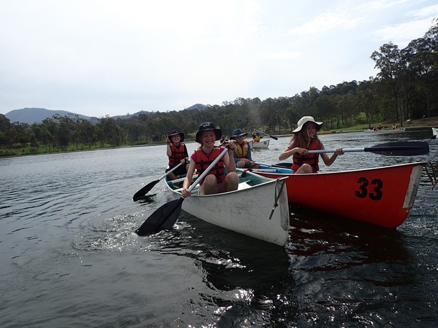 students rowing in canoes on river