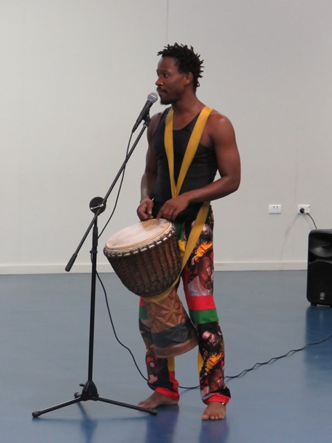 man standing at microphone holding drum